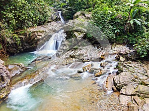 Waterfall with big rock bank in the green tropical forest