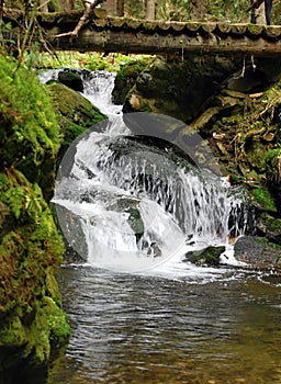 Waterfall on Bila Opava river with wooden bridge above