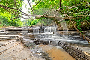 Waterfall called Tat Yai Waterfall with rock layer and green forest background in local area
