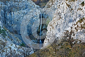 Waterfall carved into a rock wall falling into a pool in Val Rosandra photo