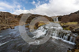 Waterfall cascade in the area of Gjain in Porsdalur in the Icelandic highlands. Oblue cloudy sky. Long exposure shot of the river.