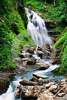 Waterfall cascade on mountain rocks. A mountain waterfall flows over the rocks