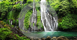 Waterfall cascade in tropical rainforest with rock and turquoise blue pond. 