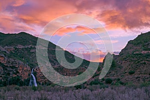 Waterfall cascading against a breathtaking sunset backdrop. photo