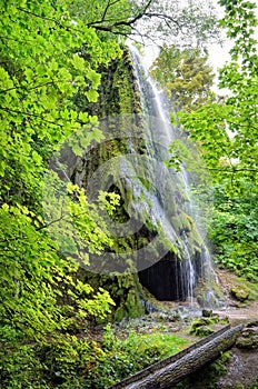 Waterfall with a cave among a green garden