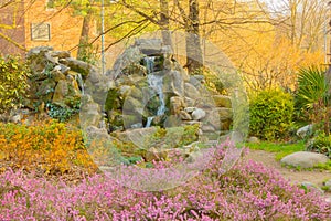 A waterfall in a corner of the flowered park