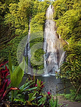 Waterfall with crystal blue water and rainbow in tropics. Jungle cascade waterfall in tropical rainforest with rock and turquoise