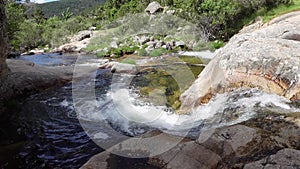 Waterfall of crystal clear water descending between the rocks of the mountain.