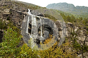 waterfall with dark mountain wall in norwegian landscape