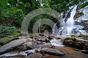 Waterfall in the deep rain forest jungle, Beautiful waterfall in green tropical forest. View of the falling water with splash in