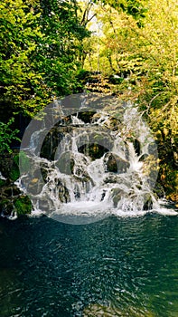 Waterfall descending through rocks surrounded by trees and greenery
