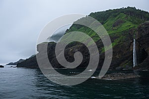 Waterfall dropping from high rocky cliffs into the ocean Sea of Okhotsk around the Shiretoko Peninsula