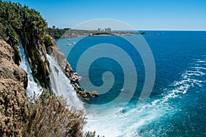 Waterfall Duden at Antalya turkey top view on the mountain with coast ferry boat on blue sea and harbor city background -