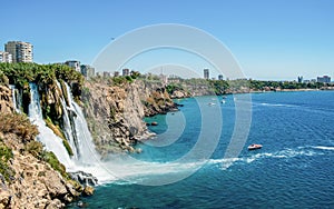 Waterfall Duden at Antalya turkey top view on the mountain with coast ferry boat on blue sea and harbor city background -