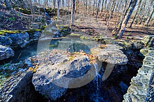 Waterfall in fall forest going down into dark cavern