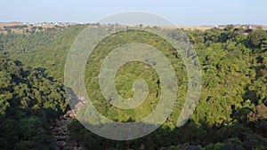 Waterfall falling from mountain with green forests and flat sky at morning