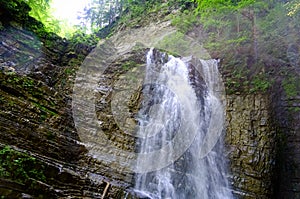 Waterfall falling from rocky cliff in forest.