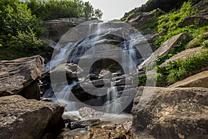 The waterfall falls down among the stone blocks.
