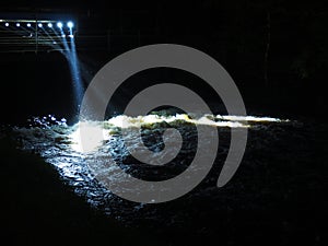 Waterfall and floodlights. Power plant at nigh