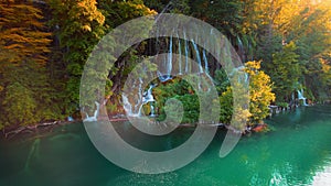 Waterfall flowing in autumn forest at national park during warm sunset light. Cascade in woods with colorful trees and