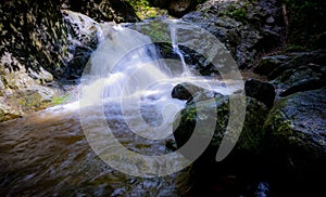 Waterfall is flowing in jungle. Waterfall in green forest. Mountain waterfall. Cascading stream in lush forest. Nature background