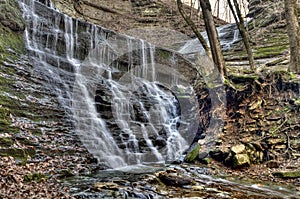 Waterfall flowing over aged and mossy grey rocks