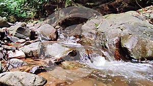 A waterfall that flows through a rock wall in the middle of the forest.