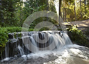 Waterfall in the forest among flowers