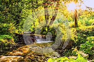 Waterfall in a forest is illuminated by the sunbeams