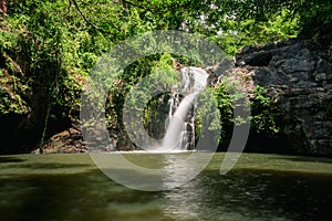 A waterfall in the forest, a natural stream of water that flows through the rocks down from a height below