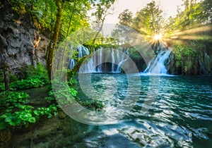 Waterfall in green forest in Plitvice Lakes, Croatia at sunset