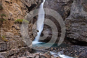 A waterfall in Jasper National Park, cascades through a narrow crack in the rocks on a long exposure to smooth out the water