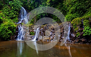 Waterfall landscape. Beautiful hidden Pengibul waterfall in rainforest. Tropical scenery. Water reflection. Slow shutter speed,