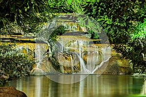 Waterfall with light from lamp in night garden