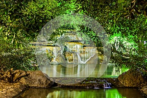 Waterfall with light from lamp in night garden