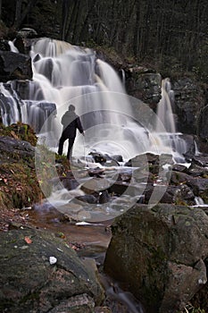 A man is watching a waterfall in the forest. 50 meter high. Ramhultafallet Seden.