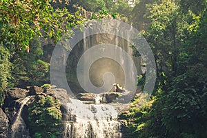 A waterfall in the middle of a jungle of the Latin American tropics with a woman at the top forming part of the scenic and photo