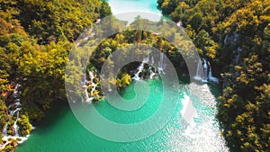 Waterfall in mountain forest with yellowed trees at autumn day. Emerald green water in Plitvice lakes National Park in