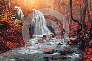 Waterfall at mountain river in autumn forest at sunset