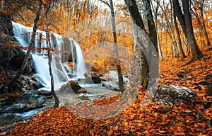 Waterfall at mountain river in autumn forest at sunset.