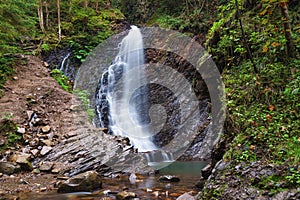 Waterfall in mountains with forest.