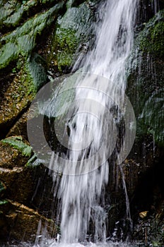 Waterfall over green mossy rocks