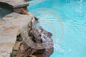 Waterfall over rocks from hot tub on higher level down to swimming pool -Refreshing and cool on a summer day