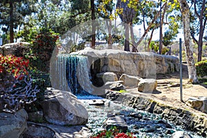 A waterfall over a stone lagoon into a river surrounded by lush green and autumn colored trees, plants with red berries