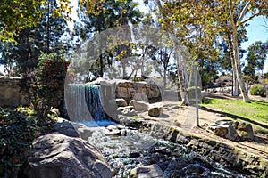 A waterfall over a stone lagoon into a river surrounded by lush green and autumn colored trees, plants with red berries