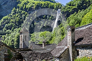 Waterfall over the tradtional stone houses with church tower in Foroglio