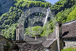 Waterfall over the tradtional stone houses with church tower in Foroglio photo