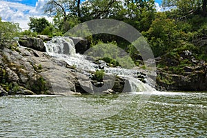 The waterfall on the river flows through and over the rocks cove