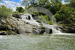 The waterfall on the river flows through and over the rocks cove