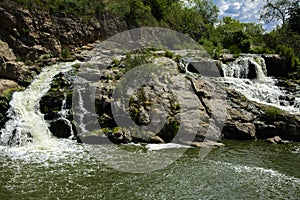 The waterfall on the river flows through and over the rocks cove